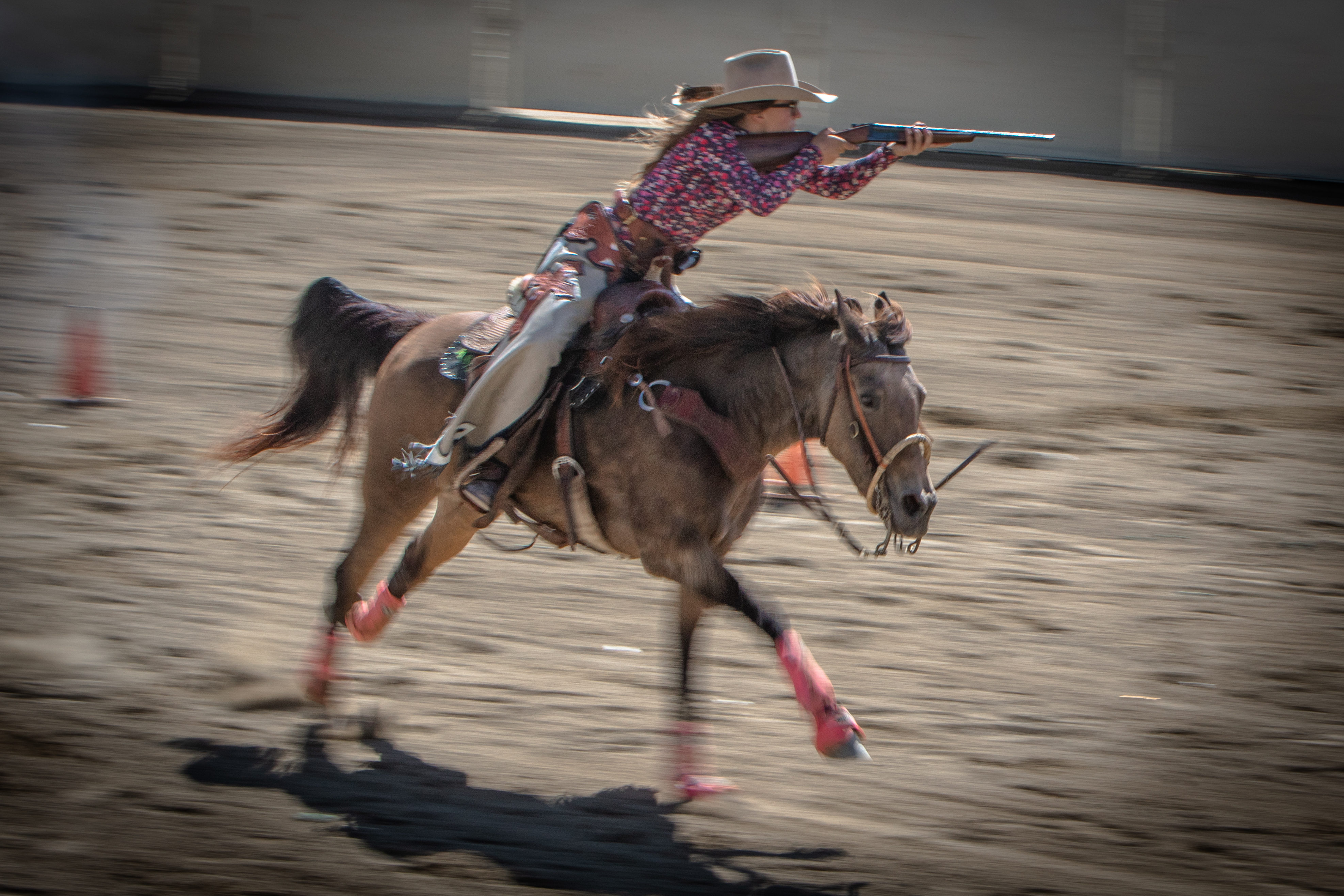 Mounted shooter on horseback at full gallop in a western arena